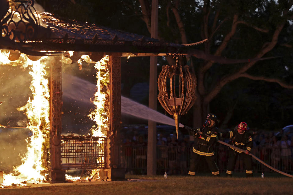 Firefighters try to control the flames during a ceremonial burn of the "Temple of Time" built as a memorial to the 17 victims of a shooting at Marjory Stoneman Douglas High School, in Coral Springs, Fla., Sunday, May 19, 2019. The "Temple of Time" public art installation was set on fire Sunday at the ceremony hosted by the cities of Parkland and Coral Springs, where the high school's students live. (John McCall/South Florida Sun-Sentinel via AP)