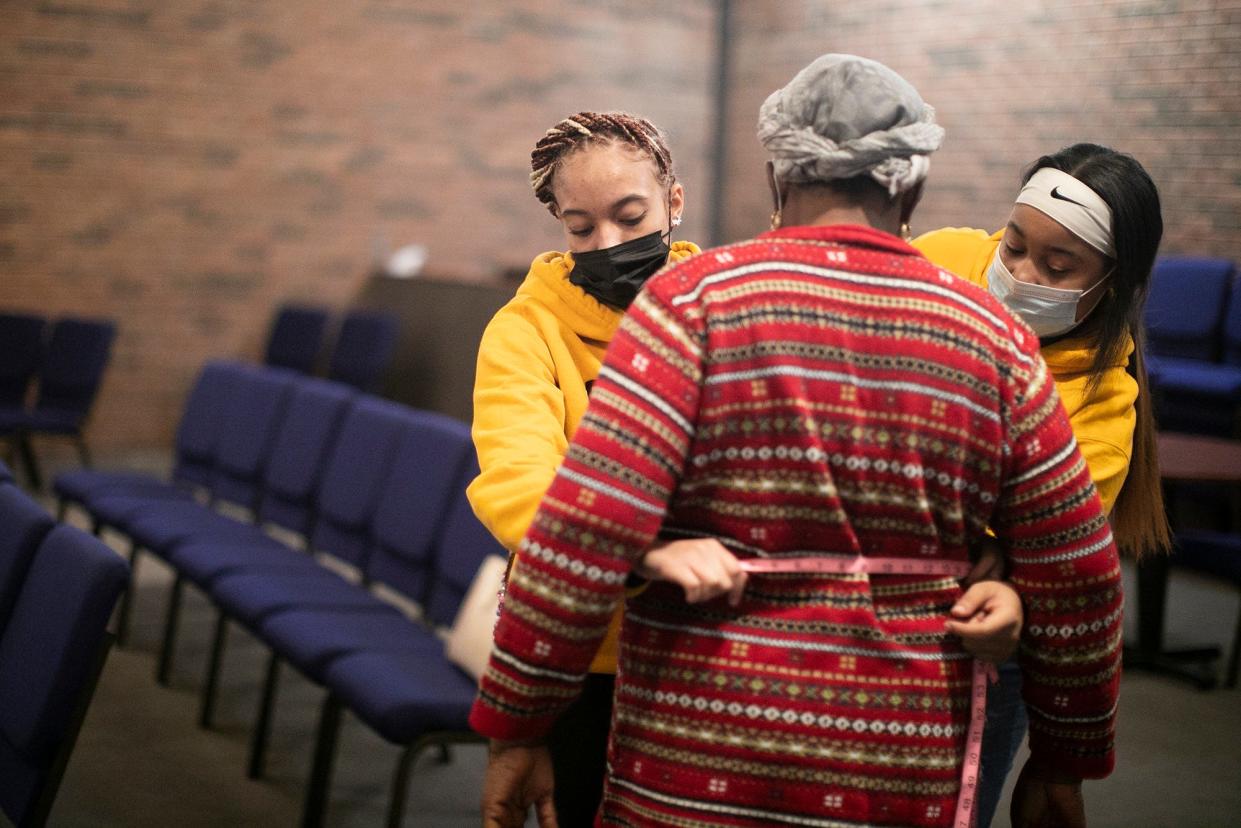 Beechcroft High School seniors Alese McNair, left, and Saraia Fisher, right, both 17, help fit Nma Tambedu, 59, for a free bra at the Church of the Good Shepherd United Methodist Church's Free Store on Friday as part of their senior community service project.