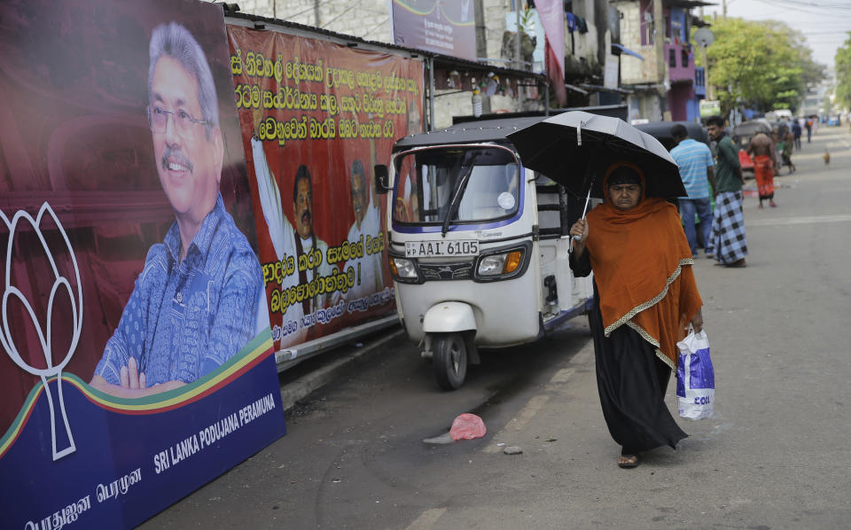 In this Wednesday, Nov. 13, 2019 photo, a Sri Lankan woman walks past election propaganda of presidential candidate and former defense chief Gotabaya Rajapaksa in Colombo, Sri Lanka. Sri Lankans will be voting Saturday, Nov. 16, for a new president after weeks of campaigning that largely focused on national security and religious extremism in the backdrop of the deadly Islamic State-inspired suicide bomb attacks on Easter Sunday. (AP Photo/Eranga Jayawardena)