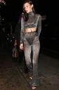 <p>In a metallic sheer turtleneck drop top and high-waisted pants with a black bra and high-cut underwear, black patent leather heeled sandals and silver hoop earrings in West Hollywood.</p>