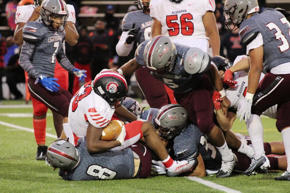 A host of Ambridge defensive players corral Aliquippa running back Tiqwai Hayes behind the line of scrimmage during Friday's Battle for the Bridge in Ambridge.