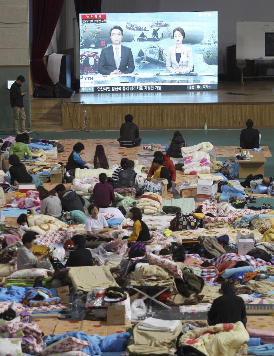 Relatives of missing passengers aboard the sunken ferry Sewol in the water off the southern coast watch a TV news program reporting government's rescue operations at a gymnasium in Jindo, South Korea, Sunday, April 20, 2014. After more than three days of frustration and failure, divers on Sunday finally found a way into the submerged ferry off South Korea's southern shore, discovering more than a dozen bodies inside the ship and pushing the confirmed death toll to over four dozens, officials said. (AP Photo/Ahn Young-joon)