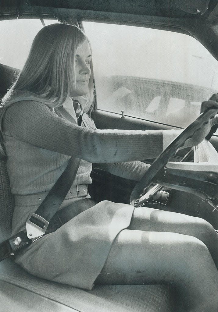 A young woman wears a seat belt in 1973.