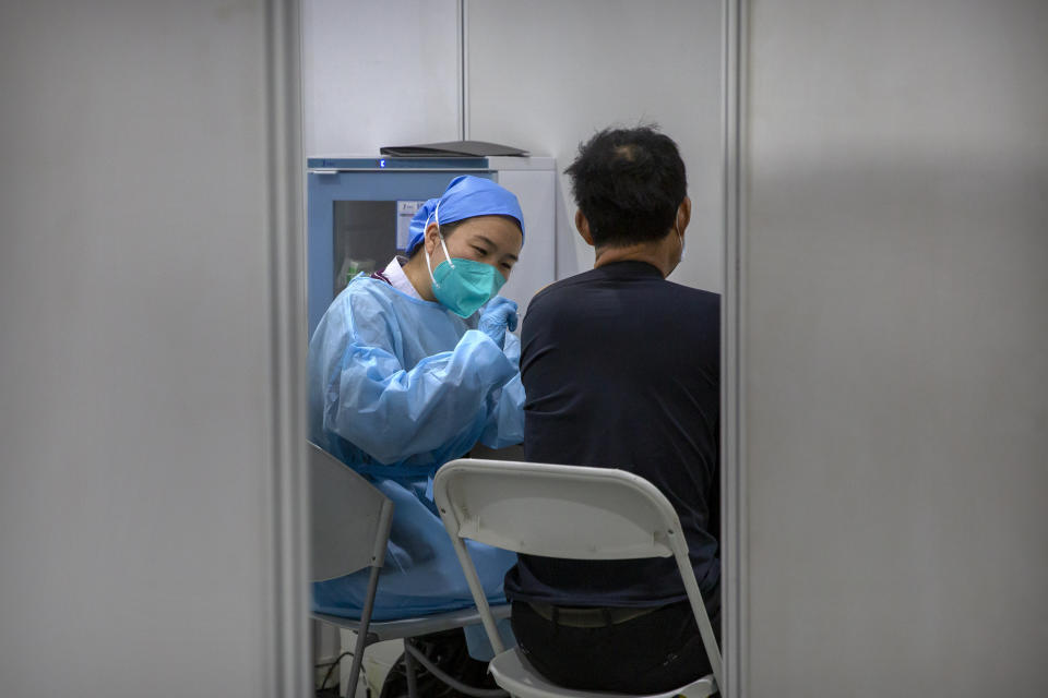 A medical worker gives a coronavirus vaccine shot to a patient at a vaccination facility in Beijing, Friday, Jan. 15, 2021. A city in northern China is building a 3,000-unit quarantine facility to deal with an anticipated overflow of patients as COVID-19 cases rise ahead of the Lunar New Year travel rush. (AP Photo/Mark Schiefelbein)