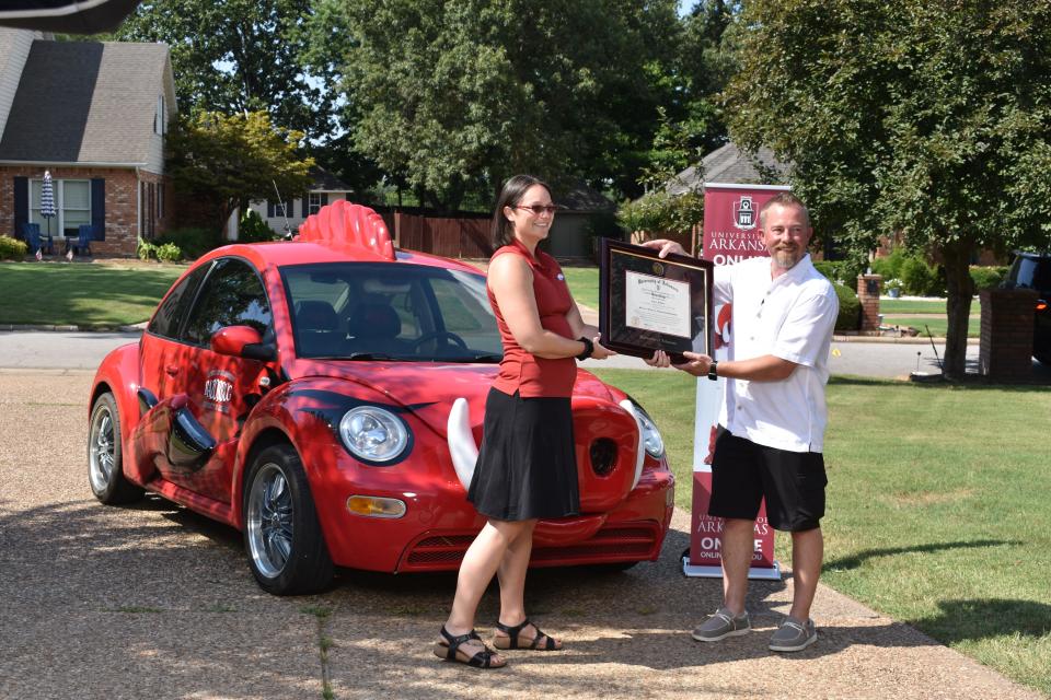 Jason Rose, right, of Fort Smith receives a framed diploma Friday for his master's degree in engineering management from Megan Whobrey, adviser and academic services coordinator in the College of Engineering at the University of Arkansas.