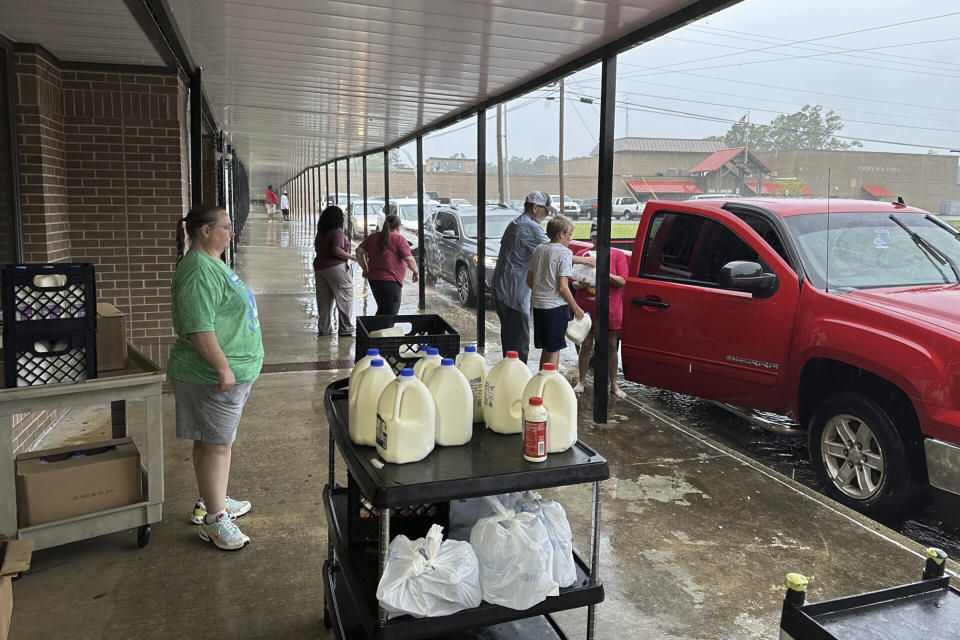 Volunteers hand out bags of groceries and jugs of milk to cars lined up at Fordyce High School in Fordyce, Ark., Wednesday, June 26, 2024. The school is one of several food distribution sites that have been set up to help residents after a mass shooting at the Mad Butcher grocery store. (AP Photo/Andrew DeMillo)