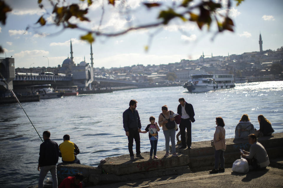 Pedestrians walk in a promenade near Galata bridge in Istanbul, Turkey, Friday, Oct. 28, 2022. Turkish President Recep Tayyip Erdogan on Friday laid out his vision for Turkey in the next century, promising a new constitution that would guarantee the rights and freedoms of citizens. (AP Photo/Francisco Seco)