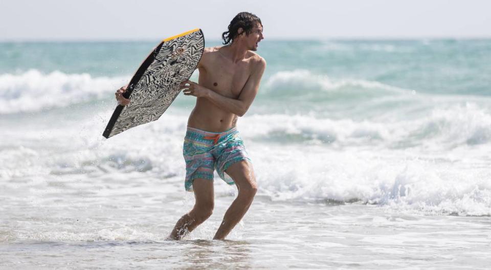 Dmitri uses a body board to catch waves near the Hollywood Beach Broadwalk as temperatures soar into the 90s on Tuesday, May 14, 2024, in Hollywood, Fla.