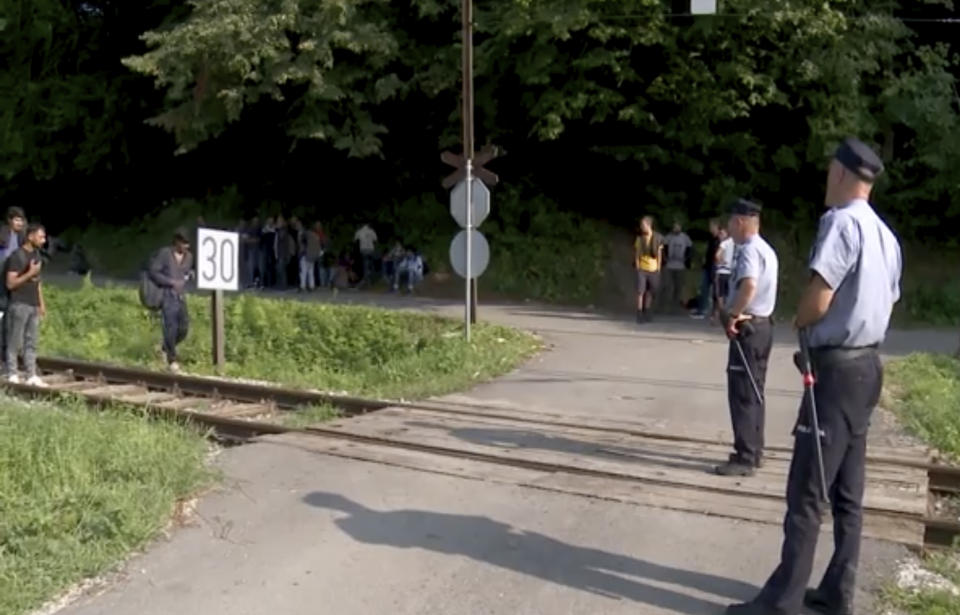 In this grab taken from video, migrants are directed off a railroad by police blocking the path, in Bosanska Otoka, Bosnia, Monday, Aug. 24, 2020. Bosnia’s quarreling ethnic leaders have put migrants amassed in the country while seeking entry to Europe at the center of a a political tug-of-war. Local authorities in the northwestern Krajina region have set up roadblocks to prevent migrants from entering the area under their jurisdiction, leaving hundreds trapped on the side of a road without access to food or shelter. (AP)