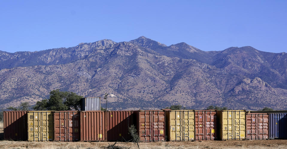 A long row of shipping containers wait for installation along the border where hundreds shipping containers create a wall between the United States and Mexico in San Rafael Valley, Ariz., Thursday, Dec. 8, 2022. Work crews are steadily erecting hundreds of double-stacked shipping containers along the rugged east end of Arizona’s boundary with Mexico as Republican Gov. Doug Ducey makes a bold show of border enforcement even as he prepares to step aside next month for Democratic Governor-elect Katie Hobbs. (AP Photo/Ross D. Franklin)