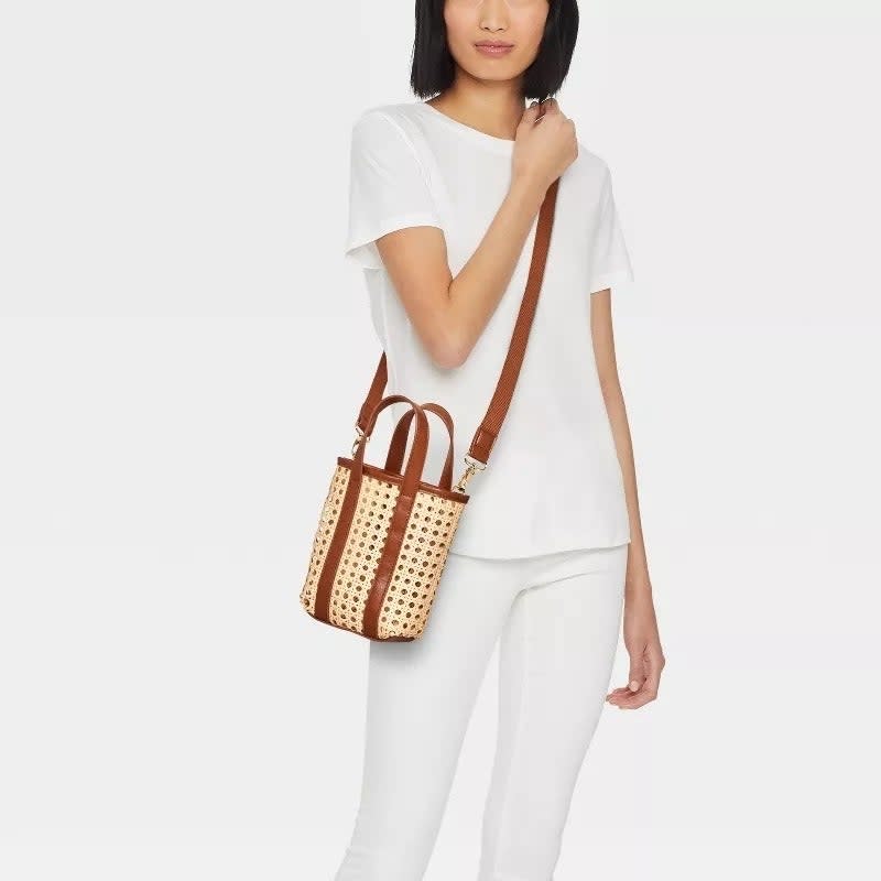 Model carrying a perforated tote bag with brown straps