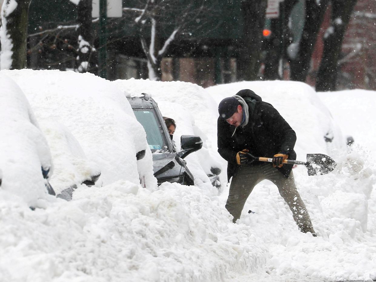 <p>A man helps a driver dig her car out from deep snow on Manhattan’s upper west side after a winter storm in New York City, New York, US, 2 February, 2021</p> (REUTERS)