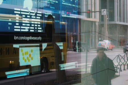 FILE PHOTO: Pedestrians pass a video advertisement for IBM at their office in Cambridge, Massachusetts, U.S., January 16, 2018.   REUTERS/Brian Snyder