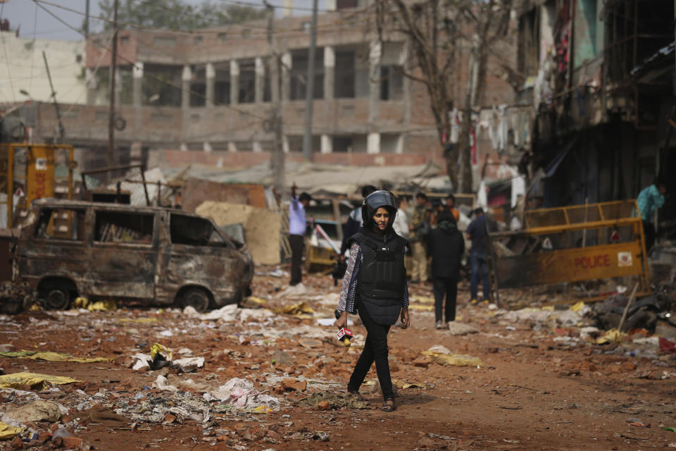 In this Thursday, Feb. 27, 2020, a television reporter holds a microphone as she walks through a street vandalized in Tuesday's violence in New Delhi, India. Reporting in India has never been without its risks, but journalists say attacks on the press during last week's deadly communal riots between Hindus and Muslims in New Delhi show the situation is deteriorating. (AP Photo/Altaf Qadri)