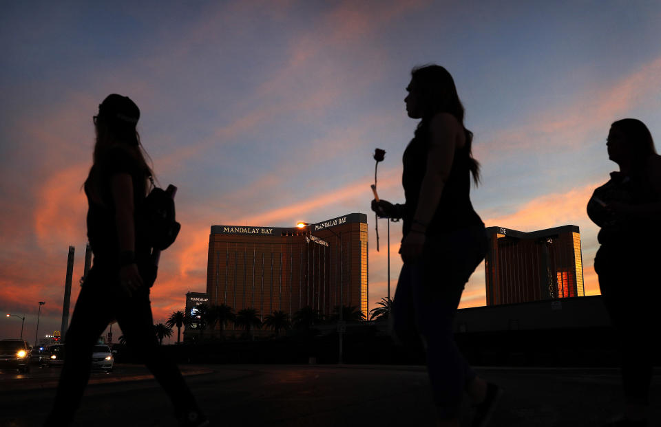 File - In this April 1, 2018 file photo, people carry flowers as they walk near the Mandalay Bay hotel and casino during a vigil for victims and survivors of a mass shooting in Las Vegas. President Donald Trump is "disappointed" the FBI couldn't figure out what specifically motivated a gunman to carry out the deadliest shooting in modern U.S. history. Trump's comments to The Daily Caller on Wednesday, Jan. 30, 2019, came a day after the FBI released its final report on the 2017 Las Vegas shooting that left 58 people dead. (AP Photo/John Locher, File)