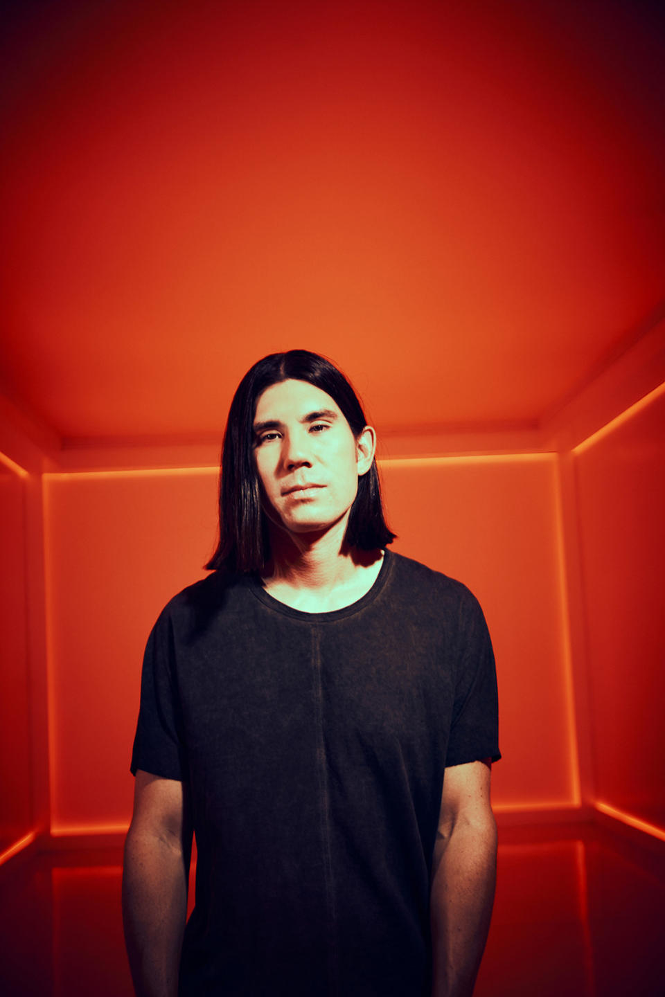 Gryffin posing in a red room with black vignette