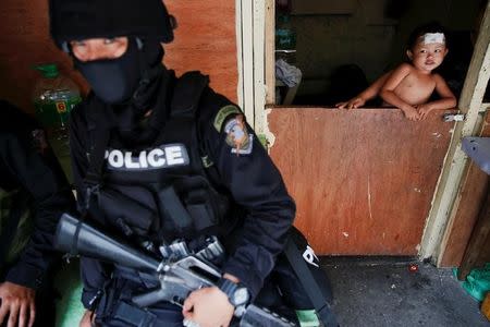 A baby looks at an armed member of a police SWAT team during a drug raid, in Manila, Philippines, October 7, 2016. REUTERS/Damir Sagolj