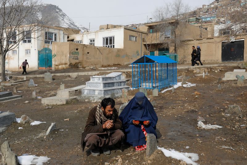 The parents of Amrullah, a child who died due to cold, pray at his grave in Kabul