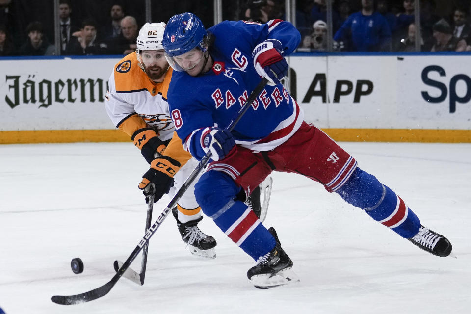 New York Rangers defenseman Jacob Trouba (8) advances the puck past Nashville Predators center Tommy Novak (82) during the second period of an NHL hockey game Sunday, March 19, 2023, in New York. (AP Photo/Bryan Woolston)