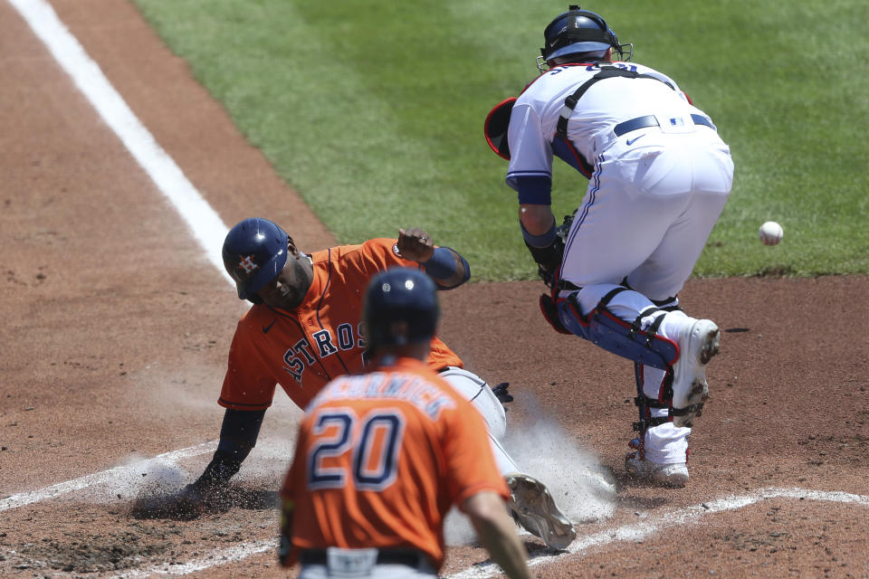 Houston Astros Yordan Alvarez, center, slides across the plate to score during the third inning of a baseball game against the Toronto Blue Jays in Buffalo, N.Y., Sunday, June 6, 2021. (AP Photo/Joshua Bessex)