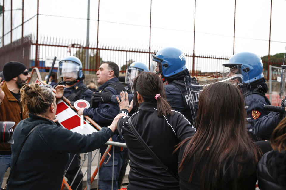 Relatives of Rebibbia prison's inmates face police after inmates staged a protest against new coronavirus containment measures, in Rome, Monday, March 9, 2020. Italian penitentiary police say six inmates protesting coronavirus containment measures at the northern Italian prison of Modena have died after they broke into the infirmary and overdosed on methadone. The protest Sunday in Modena was among the first of more than two-dozen riots at Italy's overcrowded lock-ups that grew Monday. (Cecilia Fabiano/LaPresse via AP)