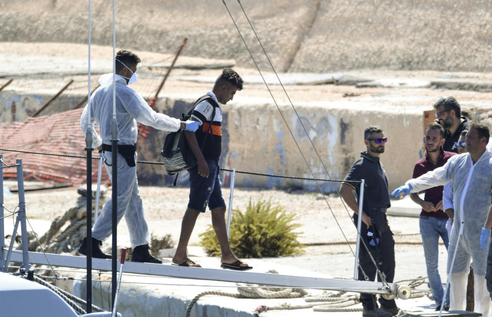 A migrant disembarks from an Italian Finance police patrol boat at the port of the Sicilian island of Lampedusa, southern Italy, Monday, Aug. 19, 2019. According to reports, a small vessel carrying more than 30 migrants was intercepted in the waters off Lampedusa and rescued by the Finance Police. 107 migrants are still on board a Spanish NGO Open Arms vessel anchored off Lampedusa because Italian Interior Minister Matteo Salvini won't let private rescue boats into his nation's ports. (AP Photo/Salvatore Cavalli)