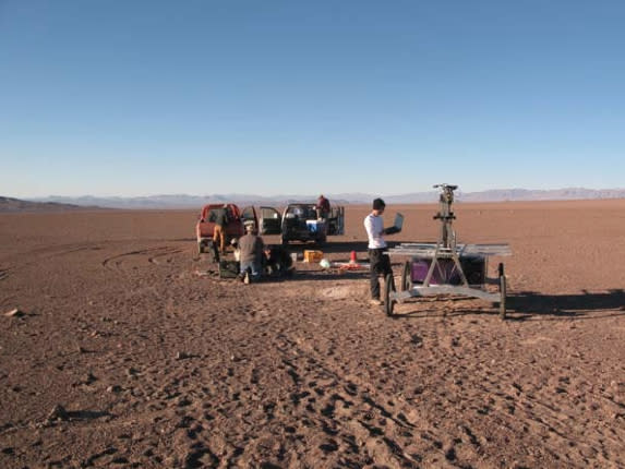 The Zoë rover being checked out at the start of its Atacama Desert traverse in June 2013. In the background are the two 4x4 trucks that were used to follow the robot. The engineers stay within communication range to monitor the robot but try to