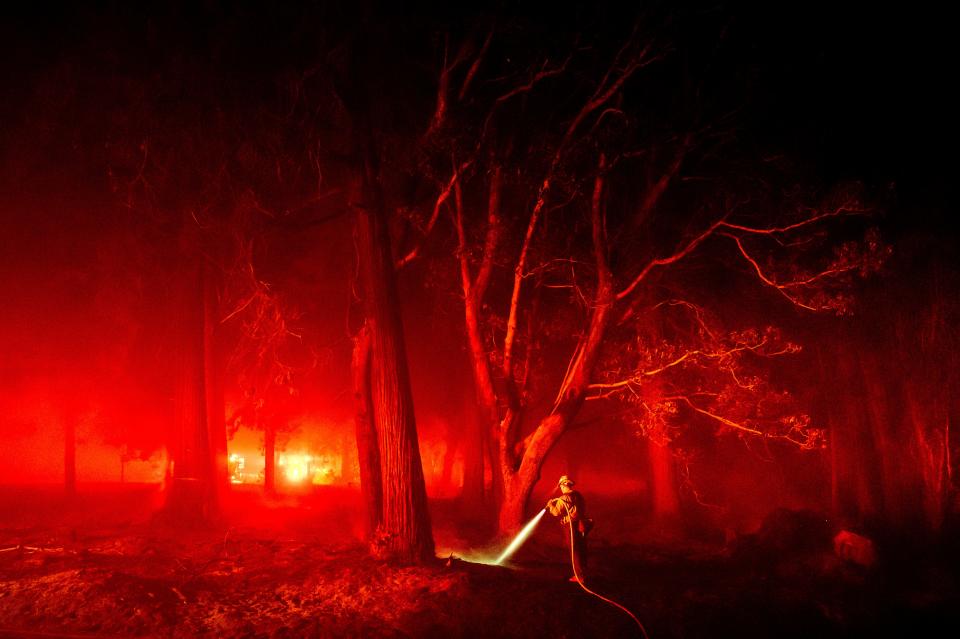 A firefighter hoses down hotspots along Foresthill Rd. as the Mosquito Fire burns in the Foresthill community of Placer County, Calif., on Tuesday, Sept. 13, 2022. (AP Photo/Noah Berger)
