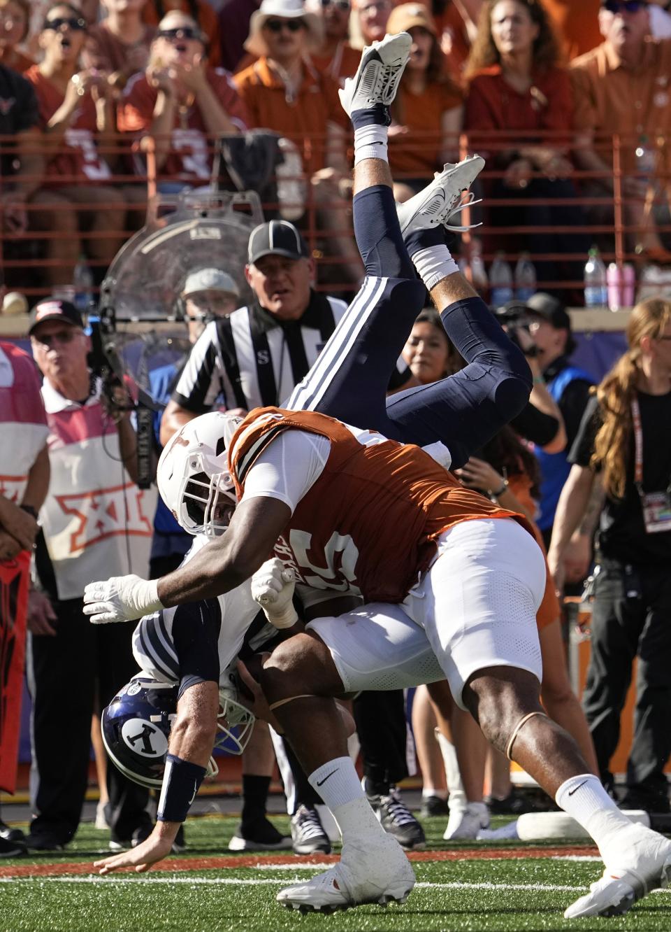 BYU quarterback Kedon Slovis, left, is upended by Texas defensive end Tausili Akana, right, during the first half of an NCAA college football game in Austin, Texas, Saturday, Oct. 28, 2023. | Eric Gay, Associated Press