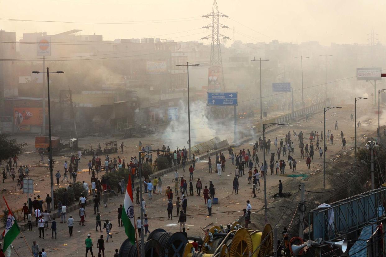 People stand on a street during clashes between hundreds of supporters and opponents of a new citizenship law: AP