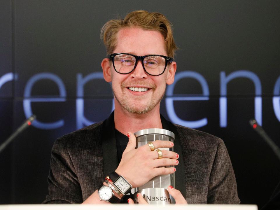 Macaulay Culkin holds a cup.