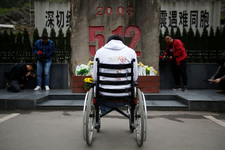 Zheng Haiyang, 27, a student who survived the earthquake and whose legs were amputated after he was rescued, mourns in front of a stele for victims of the 2008 Sichuan earthquake, next to the site of Beichuan Middle School which was buried by boulders, in the city of Beichuan, Sichuan province, China, April 6, 2018. REUTERS/Jason Lee