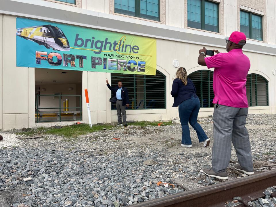 Fort Pierce City Commissioner Curtis Johnson poses below a Brightline banner on the City Hall parking garage in downtown Fort Pierce, while being photographed by Commissioner Arnold Gaines, on Wednesday, Dec. 13, 2023.