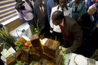 Zimbabwe's President Robert Mugabe blows out the candles on his birthday cake as he marks his 93rd birthday at his offices in Harare, Tuesday, Feb. 21, 2017. Mugabe described his wife Grace, an increasingly political figure, as "fireworks" in an interview marking his 93rd birthday. (AP Photo/Tsvangirayi Mukwazhi)