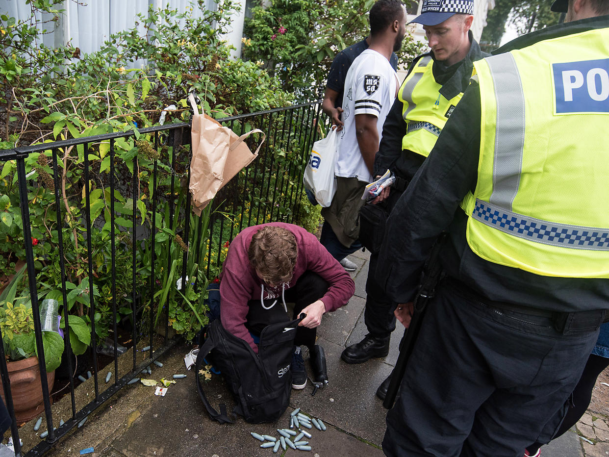 Police officers inspect the content of a man's rucksack containing canisters of nitrous oxide: Rex