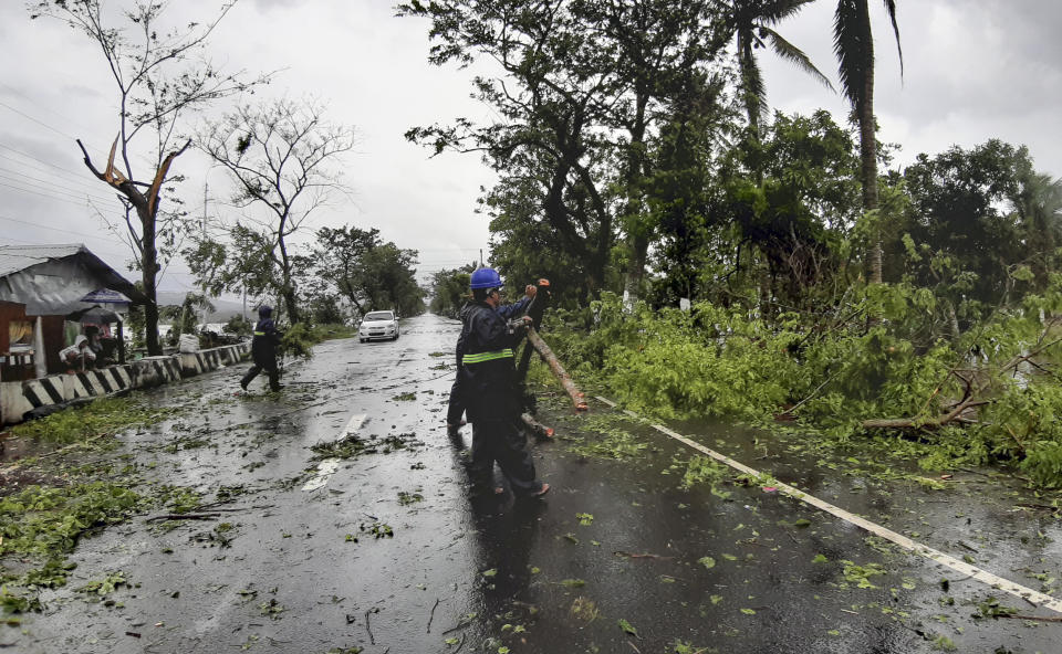 Workers clear a road of trees and branches toppled by strong winds from typhoon Vongfong as it passes by Sorsogon province, eastern Philippines on Friday May 15, 2020. More than 150,000 people were riding out a weakening typhoon in emergency shelters in the Philippines on Friday after a mass evacuation that was complicated and slowed by the coronavirus. (AP Photo/Melchor Hilotin)