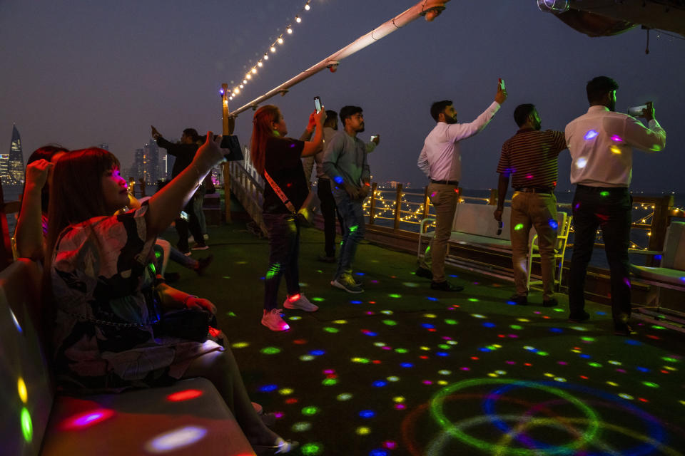 People take photographs with their phones on a traditional dhow boat, near Doha's corniche, in Qatar, Friday, Oct. 21, 2022. (AP Photo/Nariman El-Mofty)