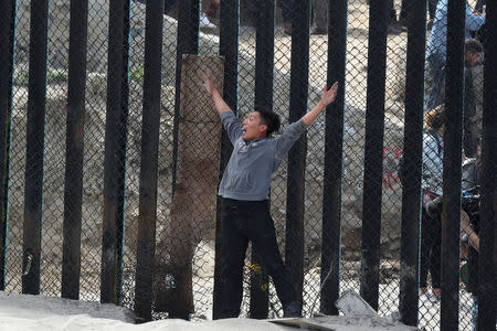 A boy who was with members of a migrant caravan from Central America and their supporters crosses the U.S.-Mexico border wall into the U.S. at Border Field State Park, in San Diego, California, U.S. April 29, 2018. REUTERS/Lucy Nicholson