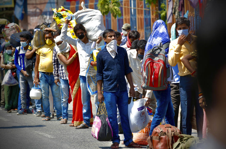 Indians line up to board trains outside New Delhi railway station in New Delhi, India, Tuesday, May 12, 2020. India is reopening some of its colossal rail network as the country looks at easing its nearly seven-week strict lockdown amid an increase in coronavirus infections. (AP Photo/Manish Swarup)