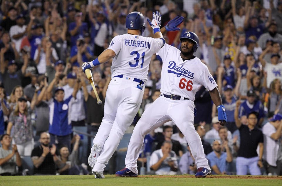 Los Angeles Dodgers' Yasiel Puig, right, celebrates with Joc Pederson afters scoring on a sacrifice by Pederson during the sixth inning against the San Francisco Giants in a baseball game Wednesday, Aug. 15, 2018, in Los Angeles. (AP Photo/Mark J. Terrill)