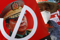 A protester holds a placard with a zero symbol over the face of Commander in chief, Senior Gen. Min Aung Hlaing, also chairman of the State Administrative Council, during an anti-coup rally in front of the Myanmar Economic Bank in Mandalay, Myanmar on Monday, Feb. 15, 2021. Myanmar's military leaders extended their detention of Aung San Suu Kyi, whose remand was set to expire on Monday, as protests continued to roil the Southeast Asian country following a military coup earlier this month. (AP Photo)