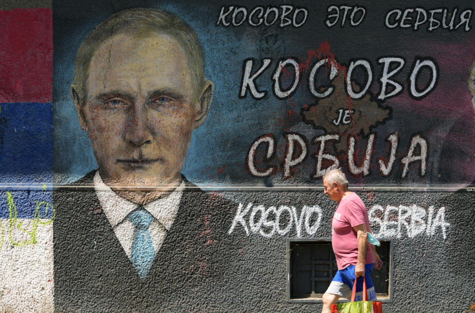 A man passes by graffiti depicting Russian President Vladimir Putin, reading: "Kosovo is Serbia" in Belgrade, Serbia, Monday, Aug. 1, 2022. Kosovo's authorities early Monday moved to ease mounting ethnic tensions in the country by delaying a controversial order on vehicle license plates and identity cards that triggered riots by minority Serbs who put up roadblocks, sounded air raid sirens and fired their guns into the air. (AP Photo/Darko Vojinovic)