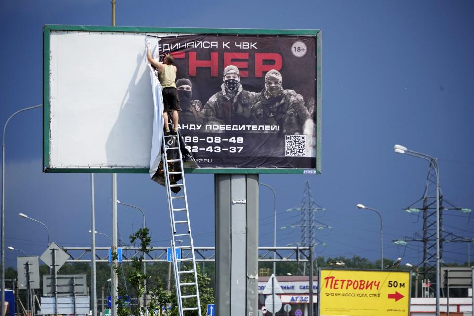 FILE - A man takes down the poster with writing reading "Join us at Wagner", which is associated with the owner of the Wagner private military contractor, Yevgeny Prigozhin, is seen above a highway on the outskirts of St. Petersburg, Russia, Saturday, June 24, 2023. The armed rebellion by a powerful mercenary group against the Russian military was over in less than 24 hours, but the disarray within the enemy’s ranks was an unexpected morale-boosting gift for Ukraine – at a time when its armed forces needed it the most. (AP Photo, File)