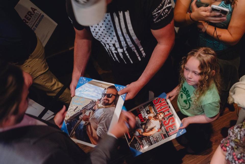 Brandon Herrera, Republican candidate for the US House for Texas’ 23rd congressional district, signs magazine covers of himself that Brandon Holloway and his daughter Wilder brought during a campaign event at the Angry Elephant, a politically themed bar, March 14, 2024 in San Antonio.