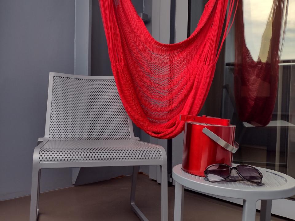 A chair with a matching table and a red ice bucket and a draped hanging red hammock.