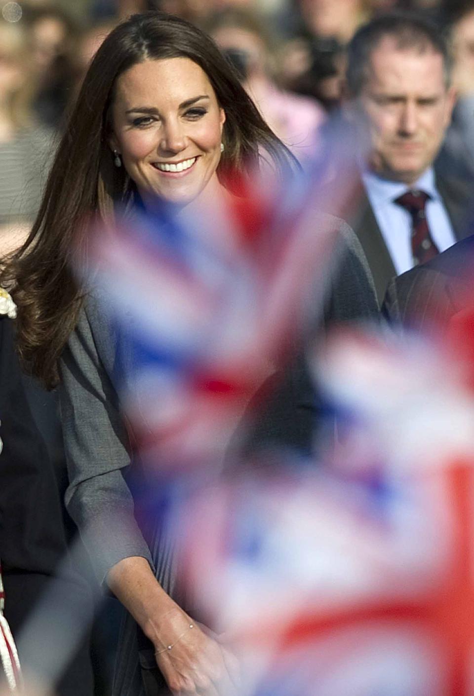 Kate, Duchess of Cambridge is seen through flags being waved by children as she arrives at an art gallery in south London Thursday March 15 2012 for an official visit. (AP Photo/ Mark Richards, Pool)