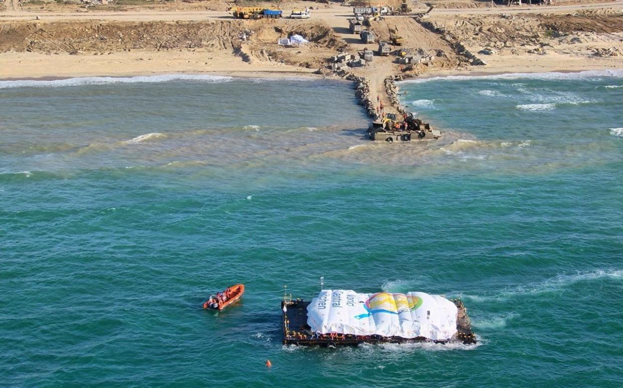 Aid is ferried from the World Central Kitchen barge to the makeshift pier on the beach