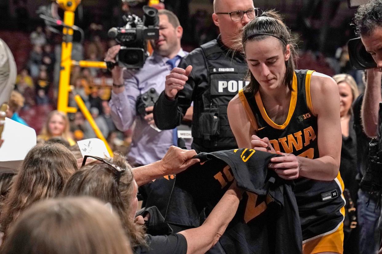 Iowa guard Caitlin Clark sign autographs for fans after a game against the Minnesota Golden Gophers at Williams Arena.