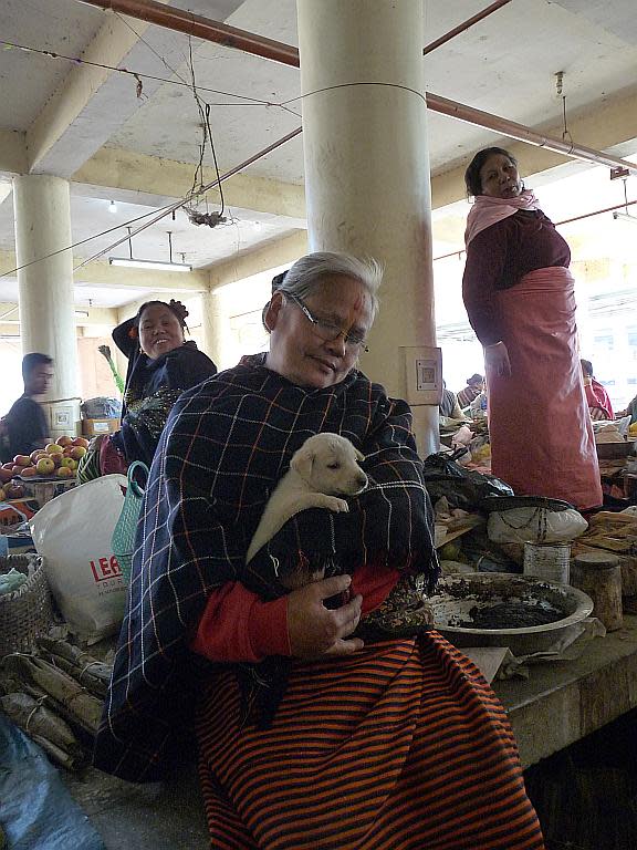 This adorable grandmother comforts a furry companion as she sells her ware in Ima Market.