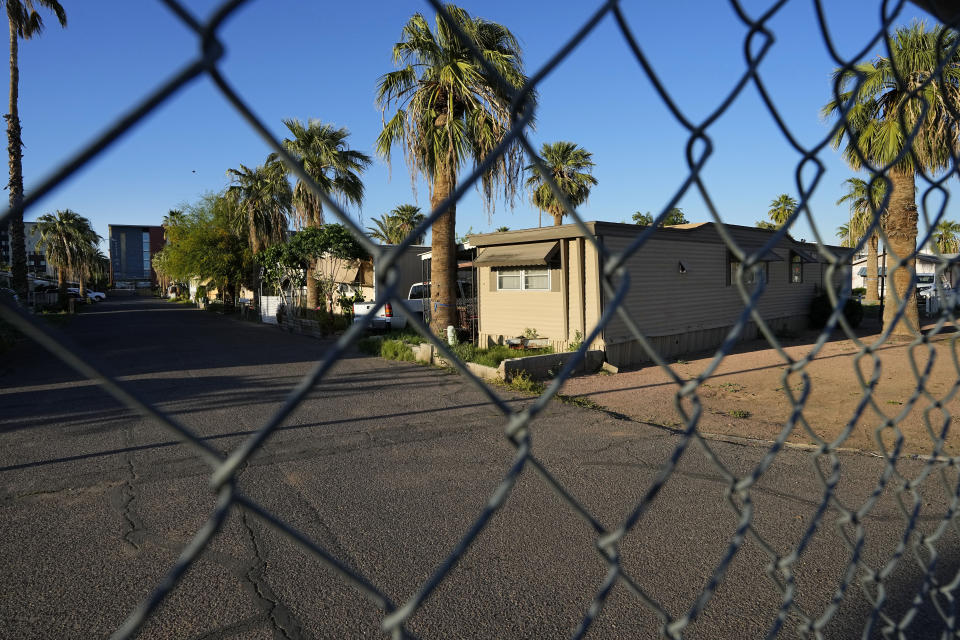 One of three entrances to the Periwinkle Mobile Home Park is fenced off from the street, Thursday, April 11, 2023, in Phoenix. The remaining residents of the park are facing an eviction deadline of May 28 due to a private university's plan to redevelop the land for student housing. (AP Photo/Matt York)